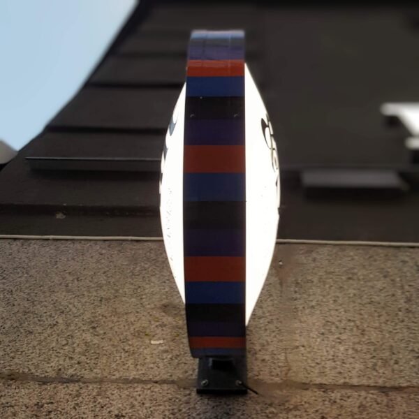 Rund dubbelsidig flaggskylt i aluminium med målad sarg och inifrån LED-belyst konvex front med vinyldekor – väggmonterad med armfäste - Bild 3