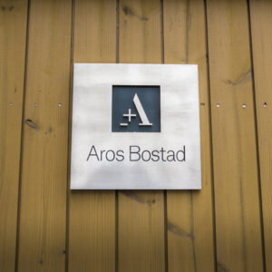 Fastighetsskylt i borstat och polerat rostfritt stål med graverad färgfylld och dekaperad logotyp och text