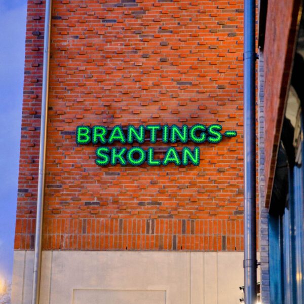 Fasadskylt med individuella profilbokstäver i grön lackerad aluminium, centrerade konturfrästa toppbokstäver och grön LED-neon i rundglansig akryl - Bild 6