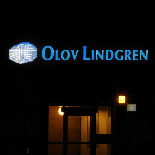 Fasadskylt med framifrån LED-belysta profilbokstäver i rostfritt stål, opalfronter med translucent vinyldekor och logotyp i blå urfräst akryl på vit akryl