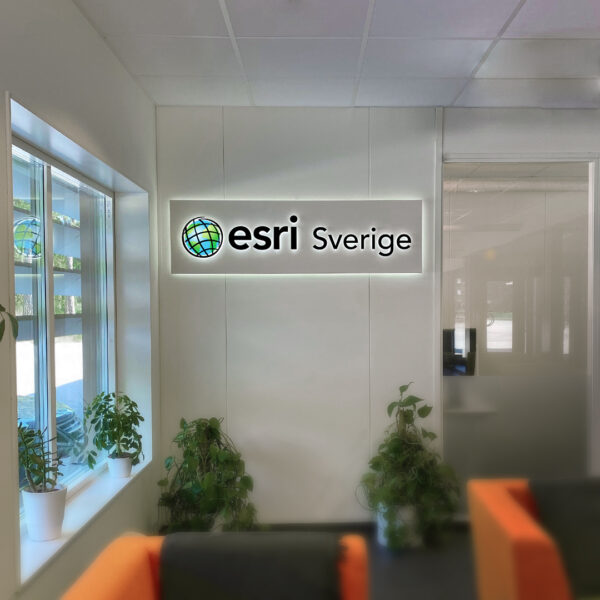 Receptionsskylt med vit bakgrundsplatta och LED-bakbelysning, svarta profilbokstäver i lackerat rostfritt stål samt dubbelbelyst logotyp med digitaltryckt dekor och akryltopp - Bild 5