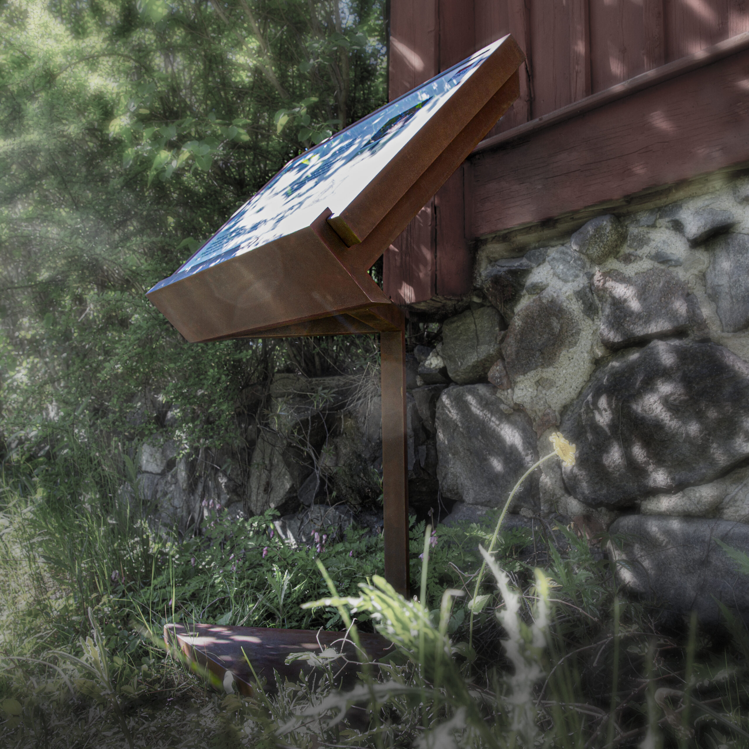 Pylonskylt i rostad corten med LED-belyst glasyta, digitaltryckt dekor, batteridrift, rörelsesensor och app-/fjärrstyrd belysning