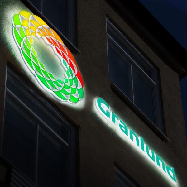 Fasadskylt med delvis kantbelyst LED-halo och frontbelysning i opalvit akryl med flerfärgad translucent dekor – logotyp och text i profilbokstäver