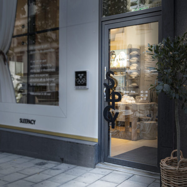 Dörrskylt i form av handtag i svartlackerat rostfritt stål – metallformad logotyp som funktionellt dörrhandtag för butikens entré