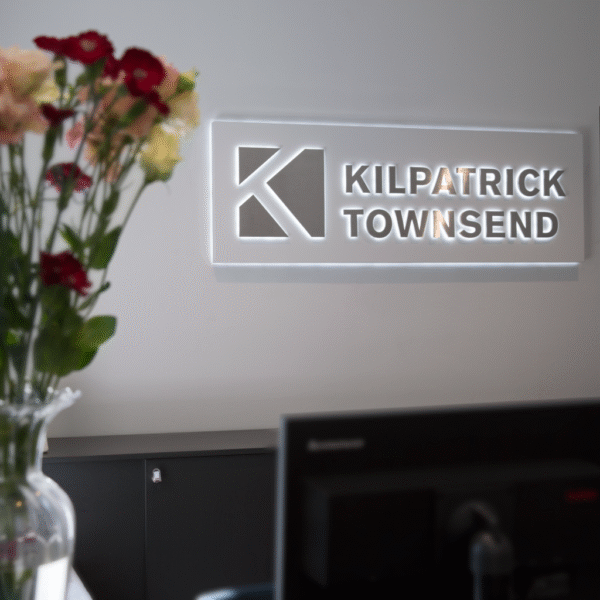 Receptionsskylt i lackerad aluminium med distansmonterade bakifrån LED-belysta profilbokstäver – halo-effekt mot bakgrundsplatta