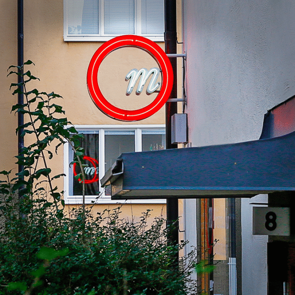 Flaggskylt i rund form med genombruten glasneonlogotyp och upphöjd kant med integrerad glasneonbelysning