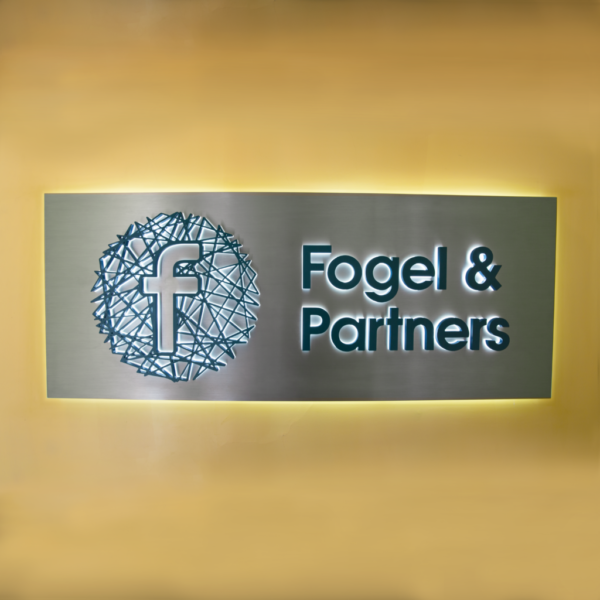 Receptionsskylt i borstat rostfritt stål med bakbelysning, laserskuren skulpturell logotyp och LED-belysta profilbokstäver med opalvit och blå delkant