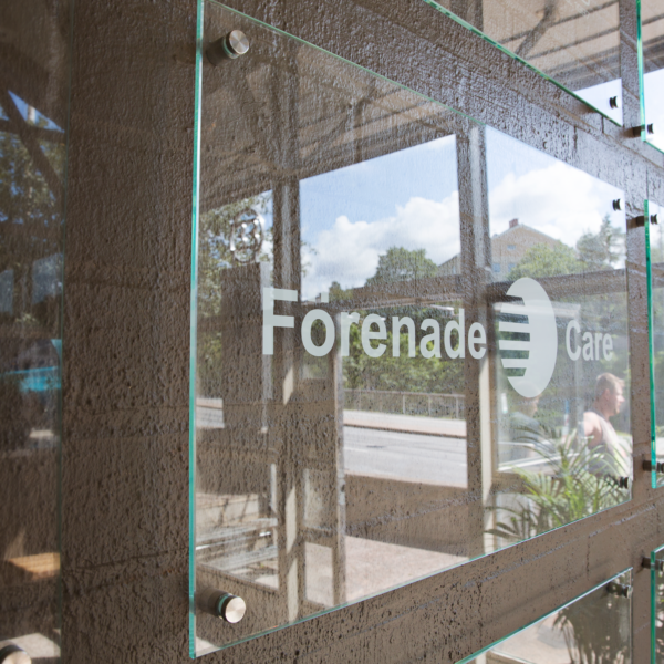 Receptionsskylt i optiwhite härdat glas med vinyldekor monterad med rostfria distansbeslag – del av en vägginstallation med flera logotyper - Bild 3