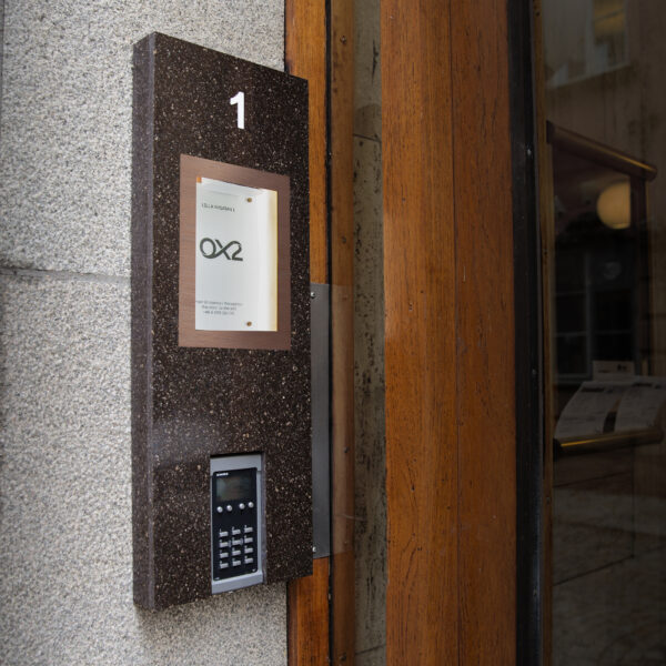 Fastighetsskylt som infoskåp i Corian med glasdörr och borstade kopparkantlister – porttelefoninkapsling med appstyrd belysning och lås - Bild 4