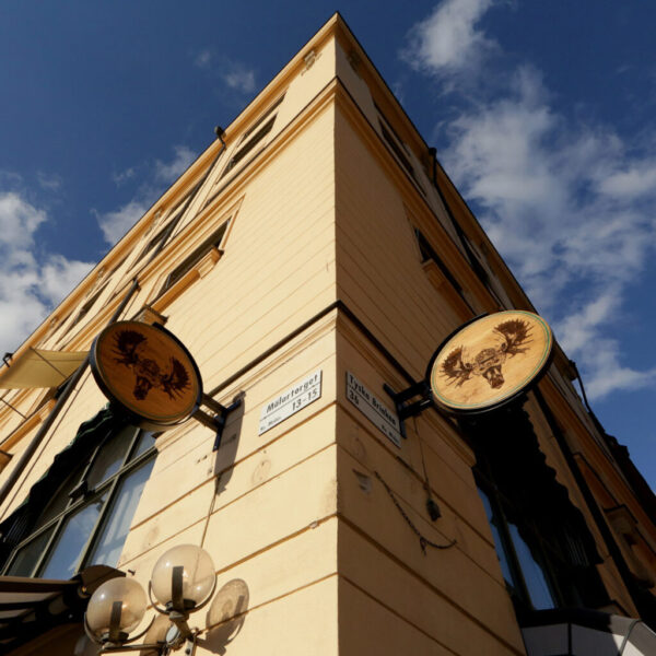 Flaggskylt i rund träform med smidesställning och lasergraverad dekor
