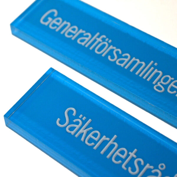 Akrylskylt i Transparent Akryl med Graverad Dekor och Blå Lack