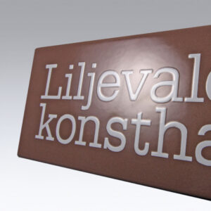 Emaljskylt med raka kanter – brun bakgrund och vit schablonerad logotyp i klassisk emaljteknik