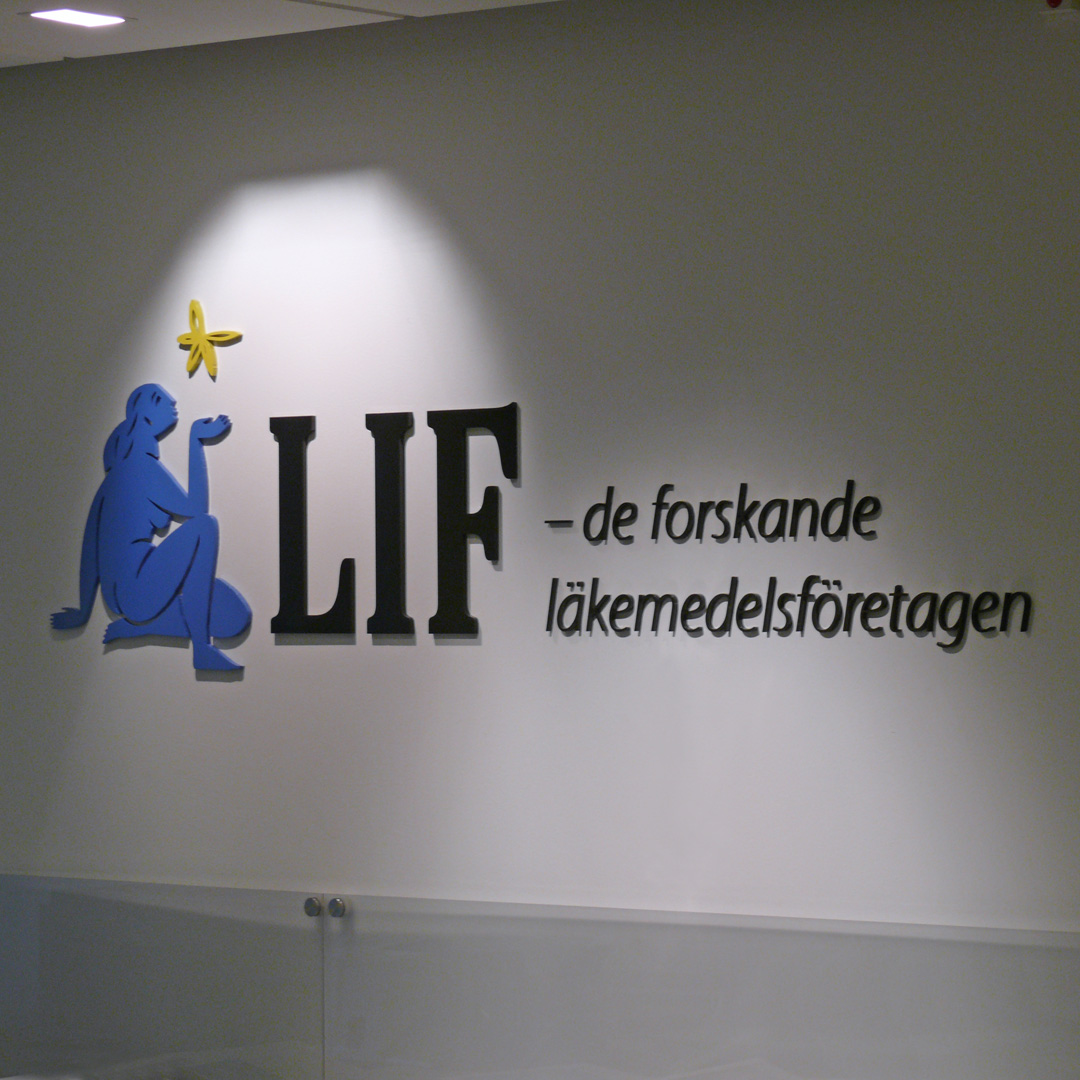 Receptionsskylt med laserskurna profilbokstäver i svart, blå och gul lackerad akryl – direktmonterad på vägg för stark visuell effekt