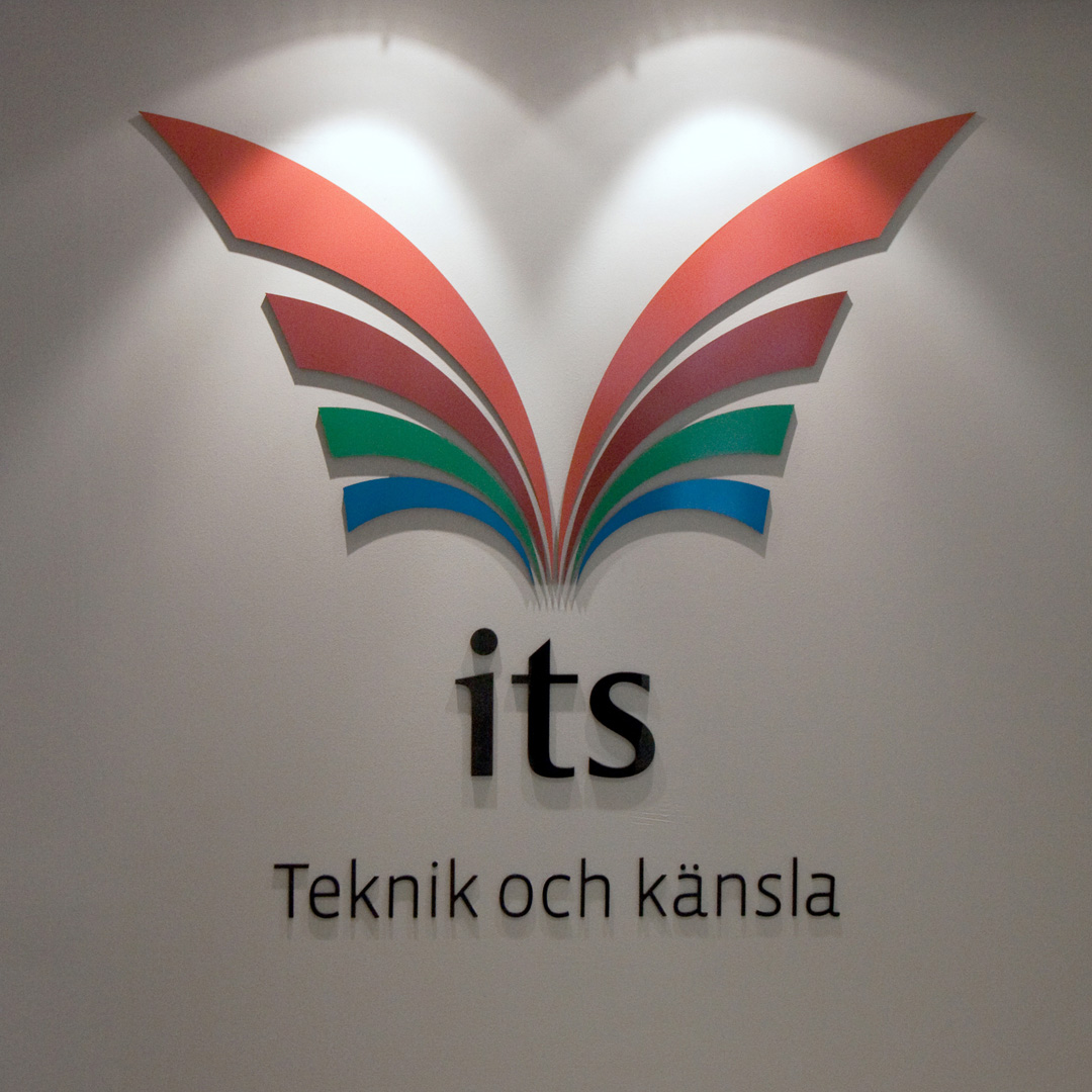 Receptionsskylt i svarta profilbokstäver och logotyp i akryl med vinyl