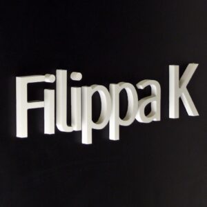 Flaggskylt Filippa K – svart plåtskylt med vit akryl logotyp